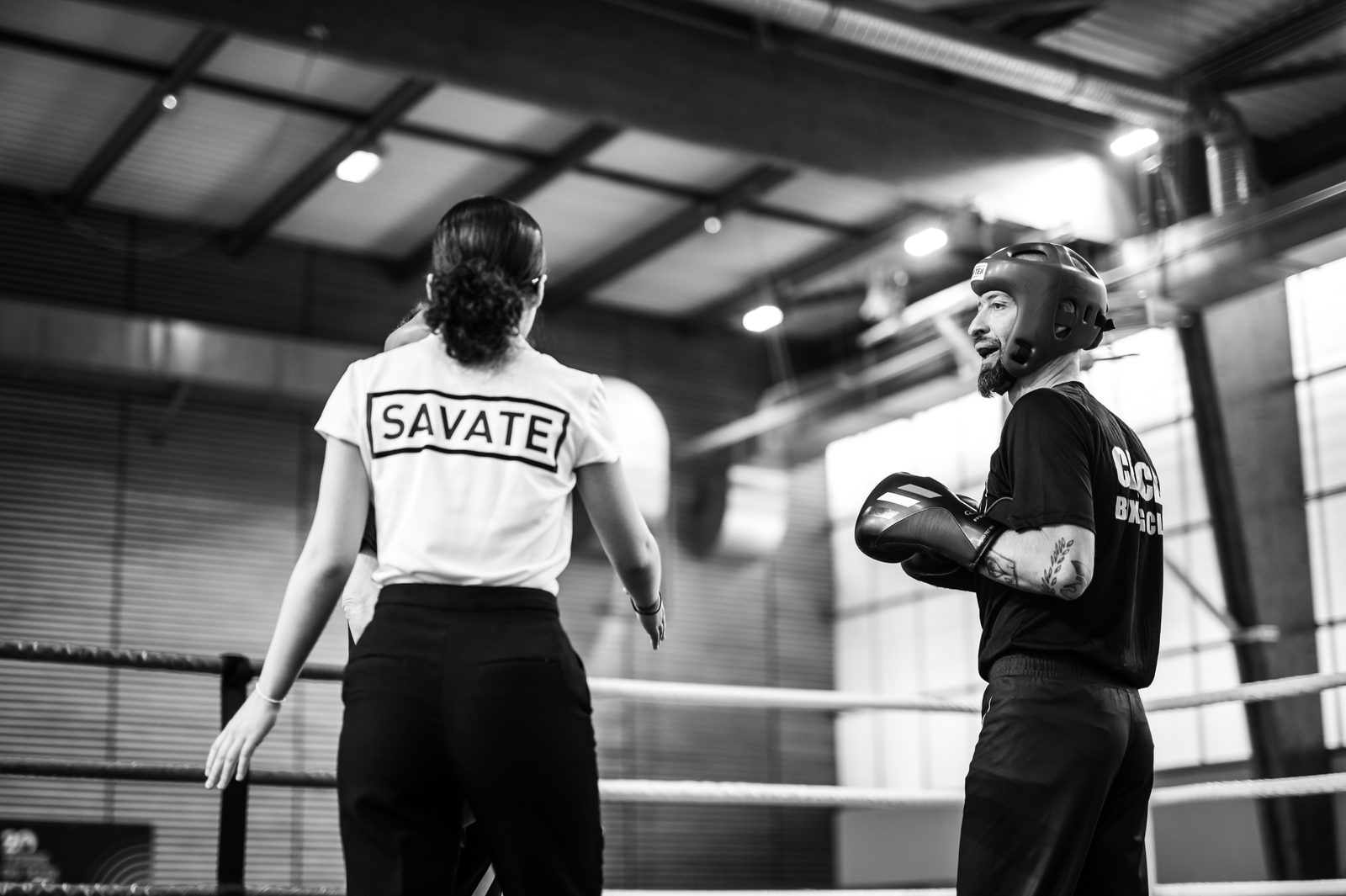 Deux tireurs face à face sur le ring, vus de dos, en tenue du club
